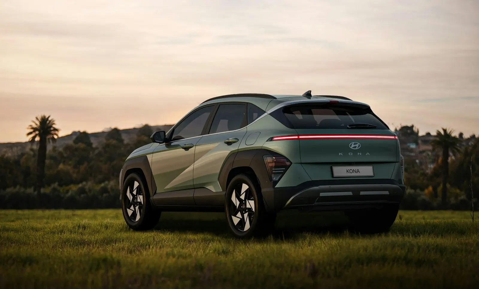 Green Hyundai Kona parked on grass at sunset